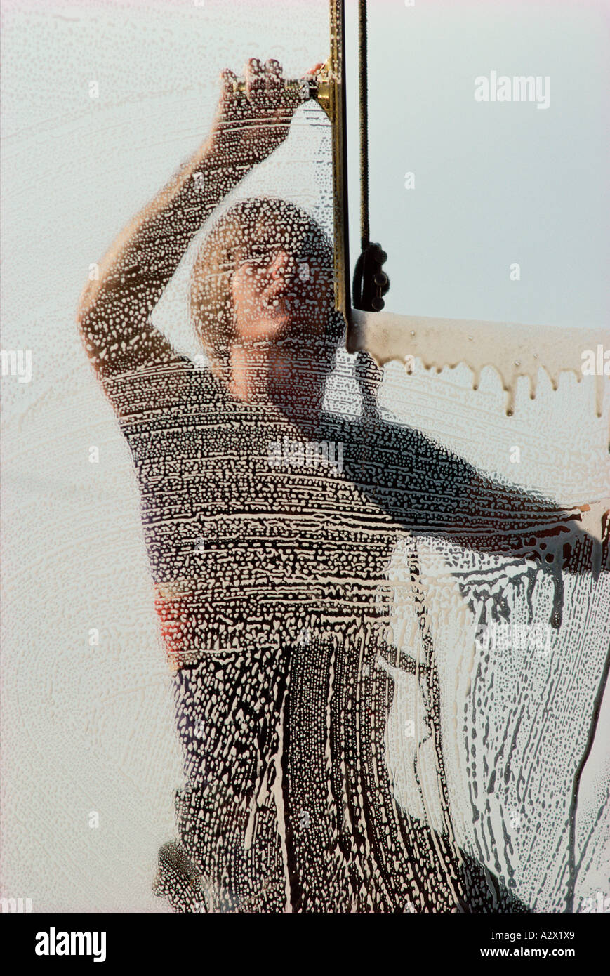 Window cleaner using squeegee. View through soapy glass. Stock Photo