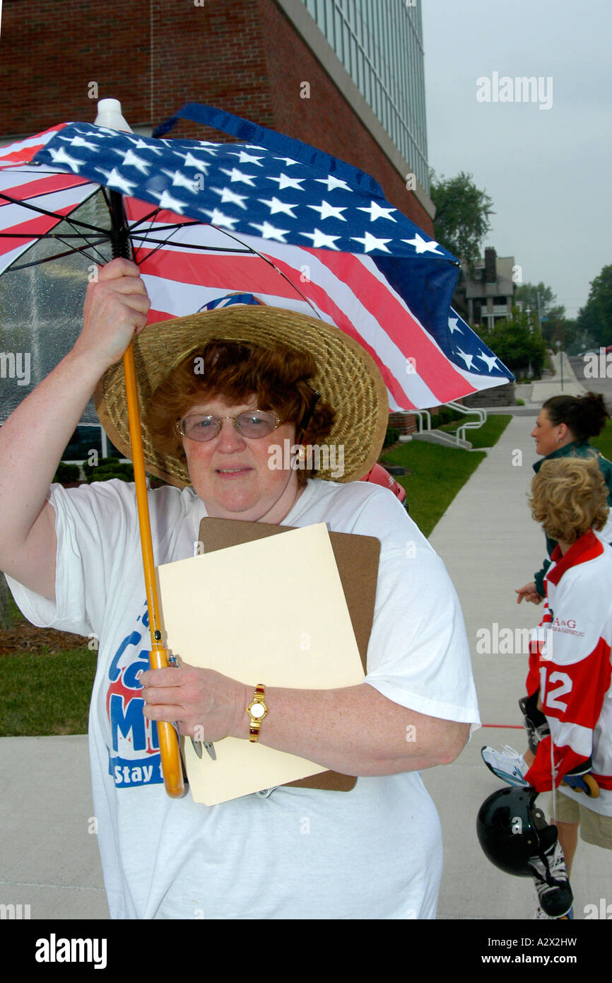 Woman sheltering under a stars and stripes umbrella.at a parade in Detroit Michigan MI. Stock Photo