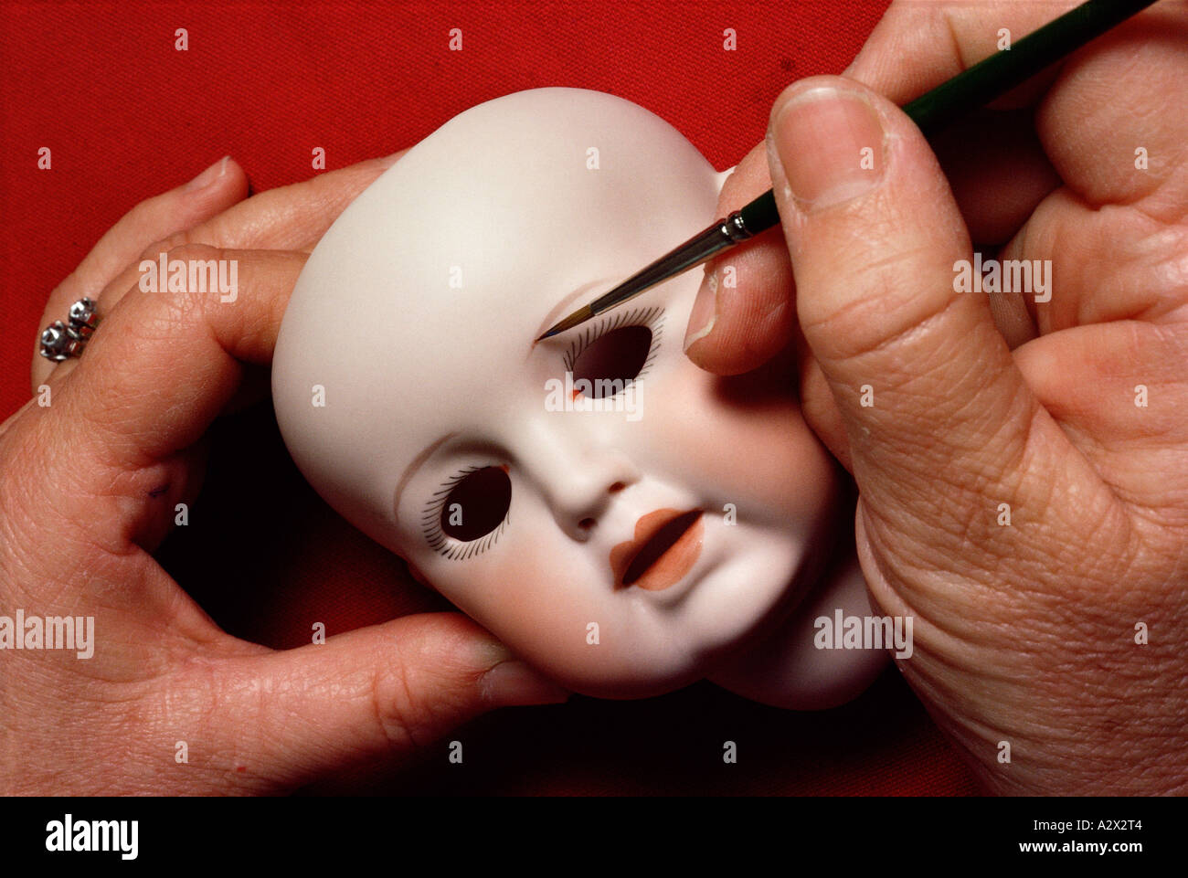 Close-up of hand painting doll's face. Stock Photo