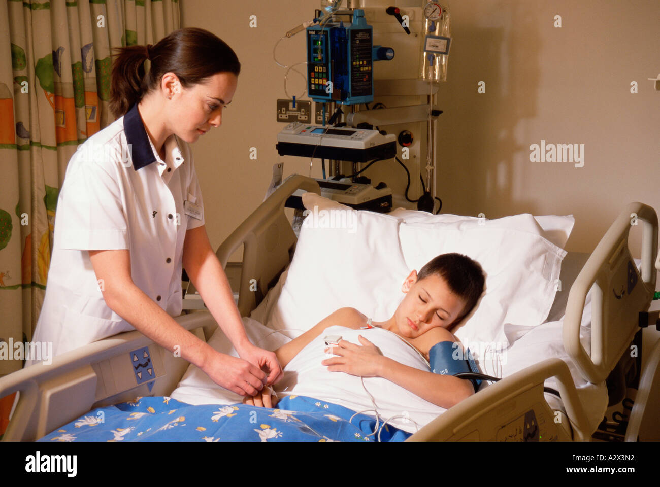 Hospital. Paediatrics. Paediatrician. Intensive care nurse at bedside of young boy patient. Stock Photo