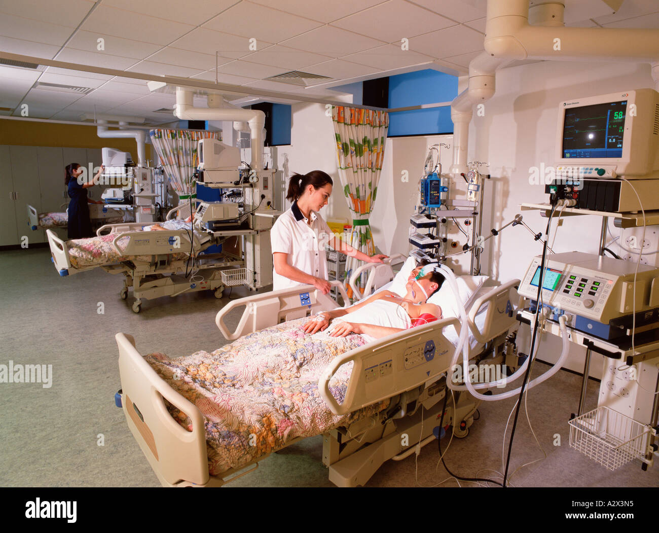 Hospital nurses tending to male patients in intensive care unit. Stock Photo