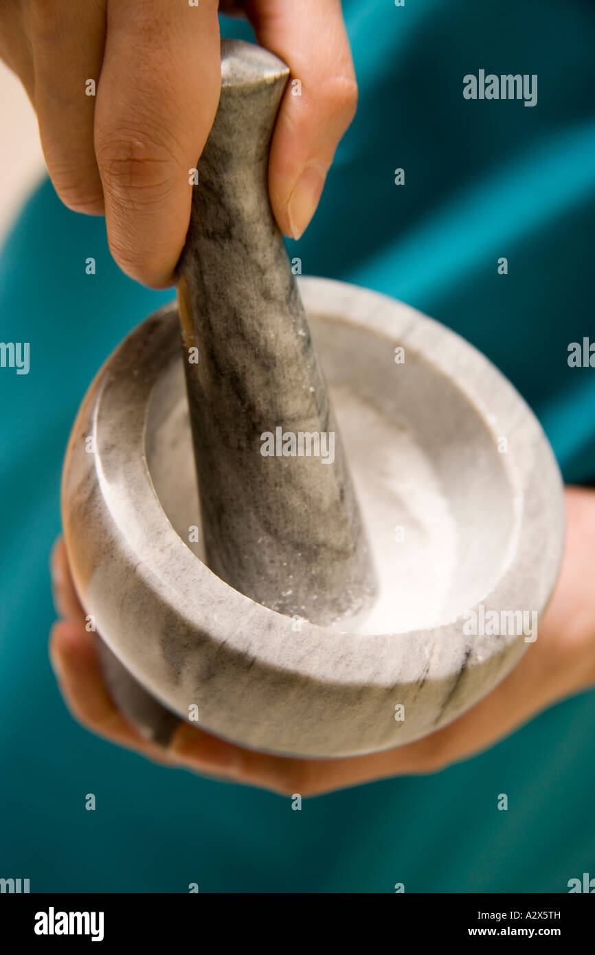 Mortar and pestle being used to grind up substances into a fine white