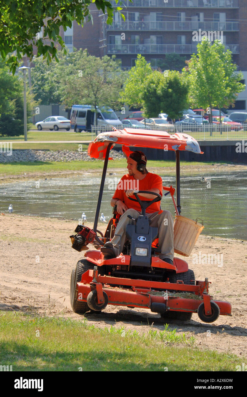 Professional lawn care worker operating a zeroturn mower in a city