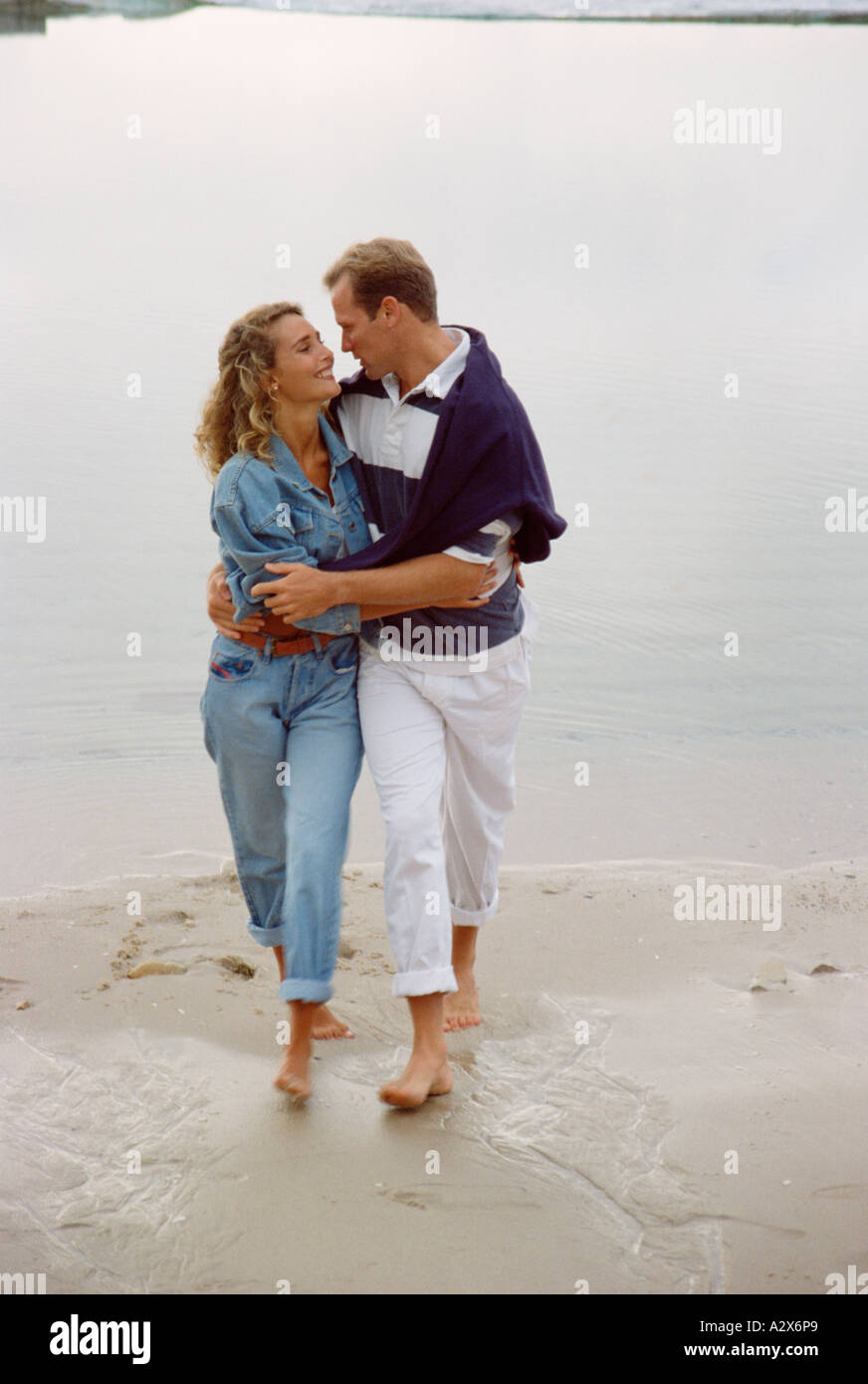 Young couple walking barefoot on the beach. Stock Photo