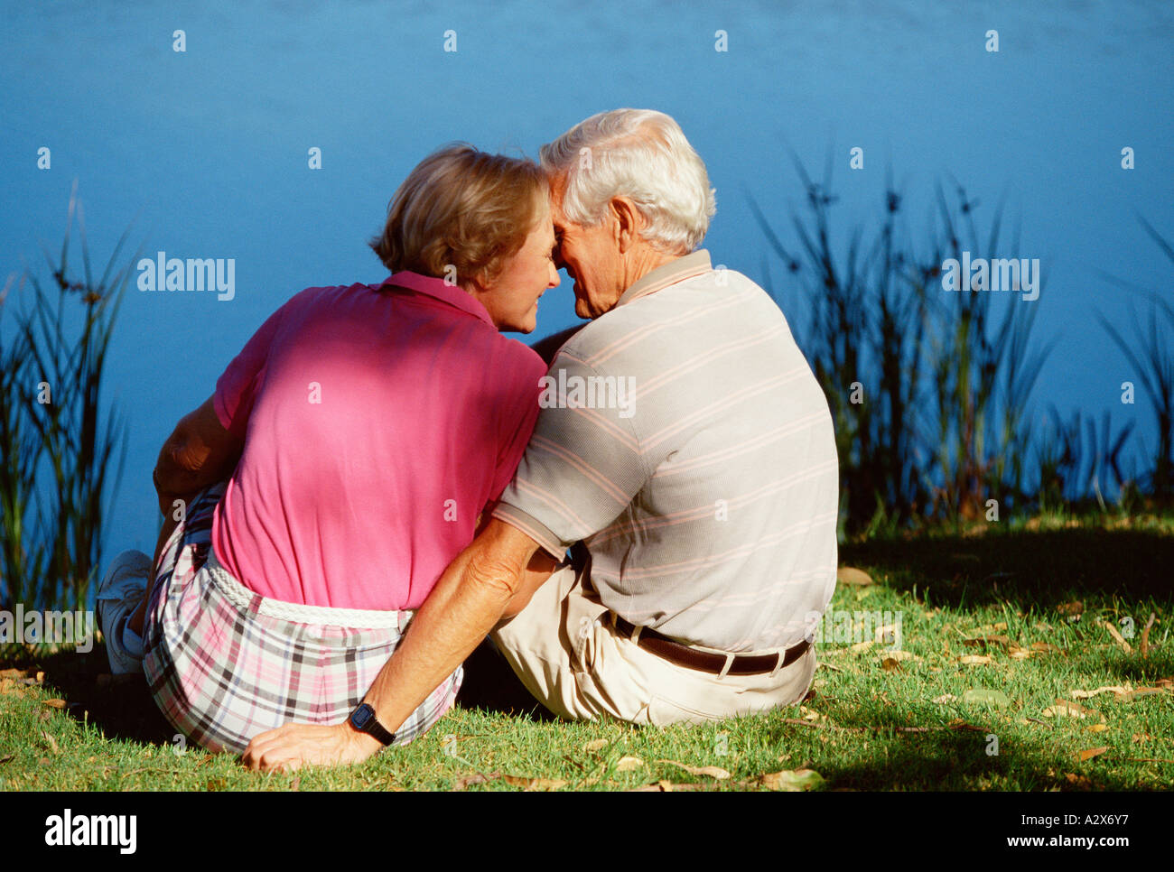 Senior couple outdoors sitting on river bank. Stock Photo