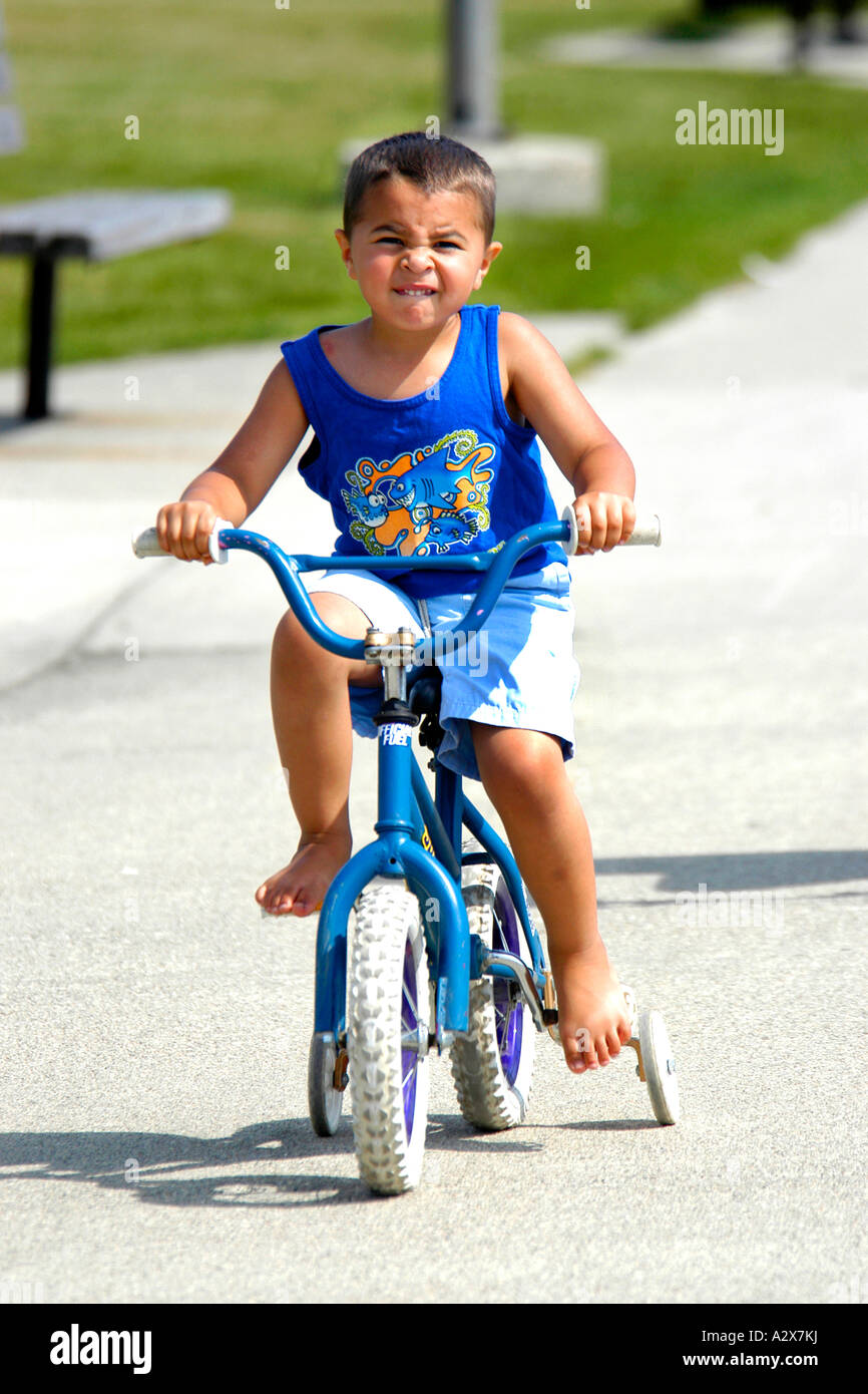 Pre-K male riding his bicycle fitted with stabilizers Stock Photo