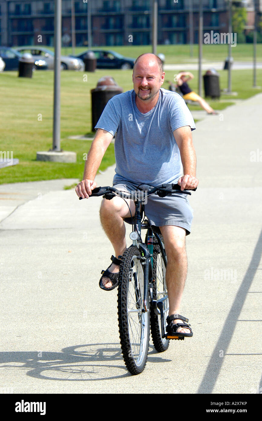 Adult male riding a bicycle but not wearing a protective helmet. Stock Photo