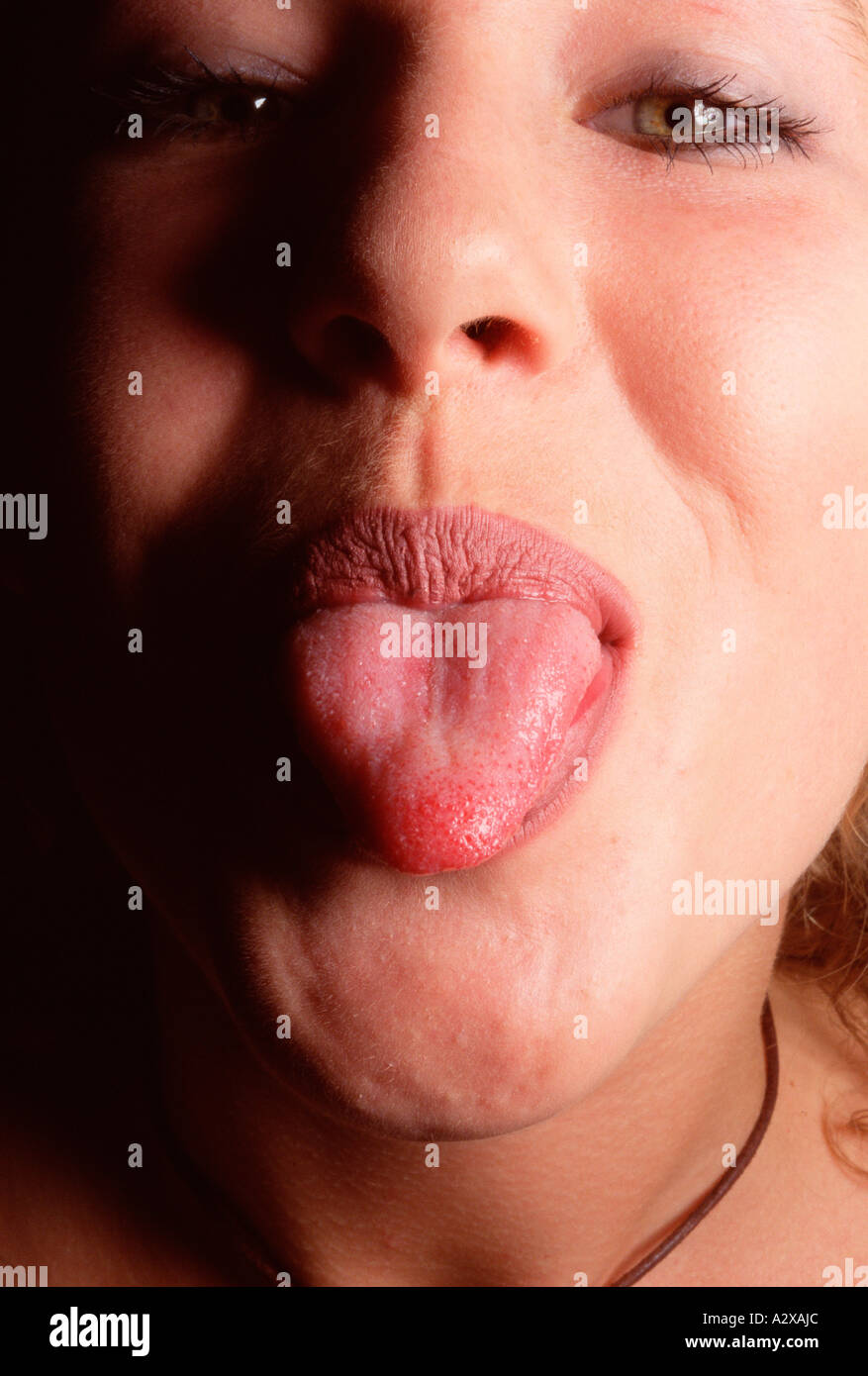 Close-up of young teenage girl sticky out her tongue in a cheeky, rude gesture. Stock Photo