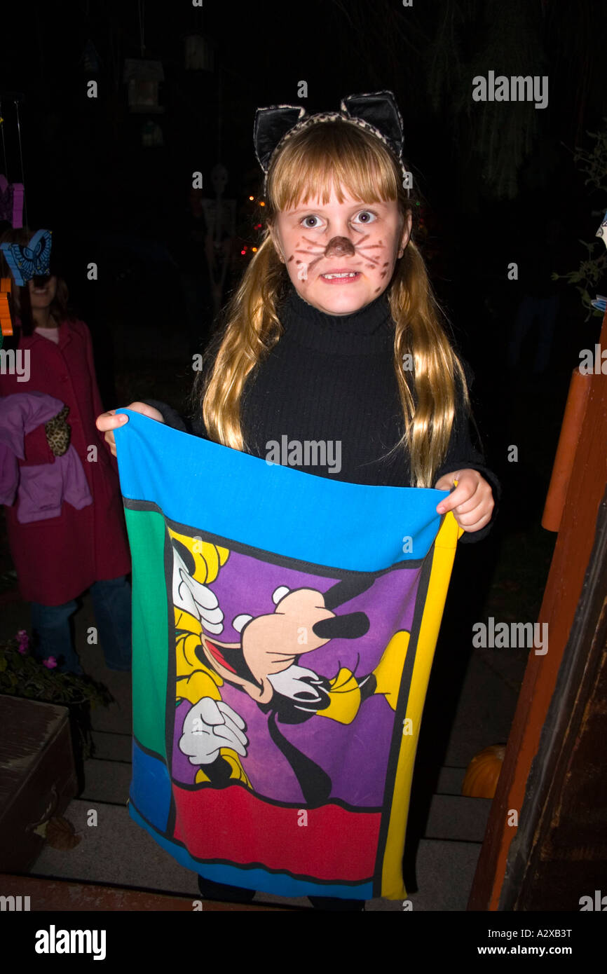 Halloween trick or treater in a cat costume with Walt Disney Goofy collection bag age 8. St Paul Minnesota USA Stock Photo