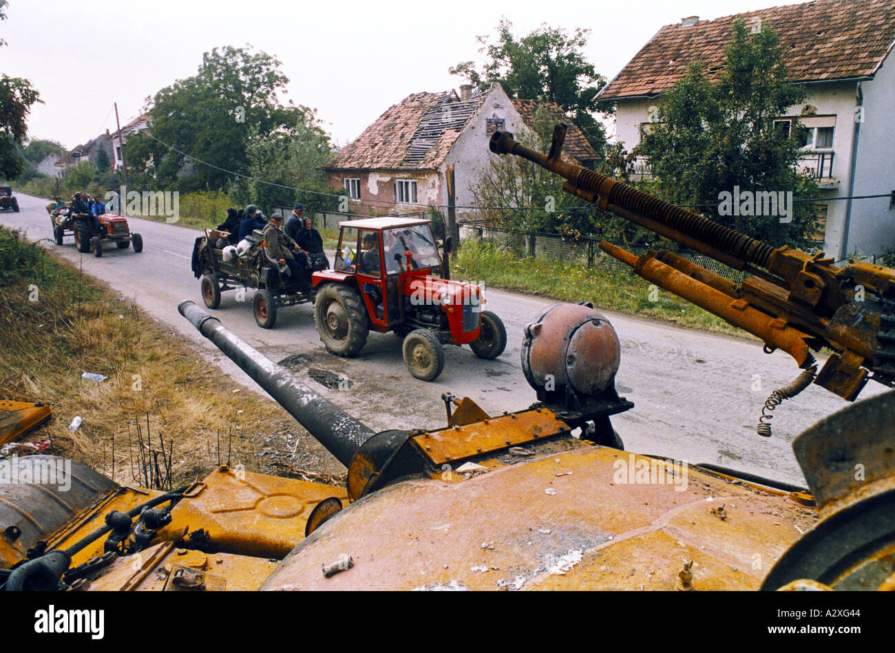 Croatian re-capture of Krajina, Aug 95 : Krajina Serb refugees in convoy to Serbia drive past burnt out Serb tank near Petrinja Stock Photo