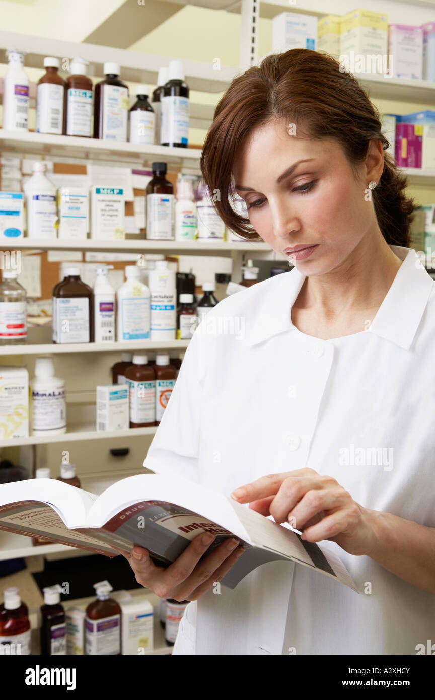 Female pharmacist looking at book in pharmacy Stock Photo Alamy