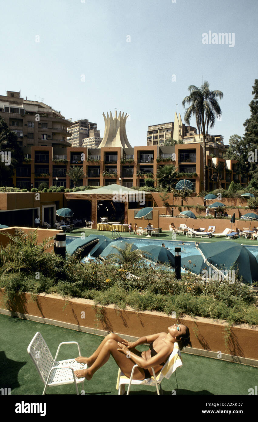 coverage of the gulf womann sunbathing wearing black bikini eye protector goggles sitting in a white chair with her feet up on another beside the swimming pool at the marriot hotel cairo 1990 Stock Photo