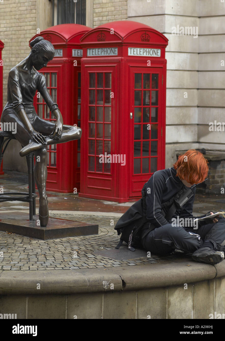 Redhead girl reading by the Young Dancer bronze statue by Enzo Plazzotta  in Broad Court Covent Garden London Stock Photo