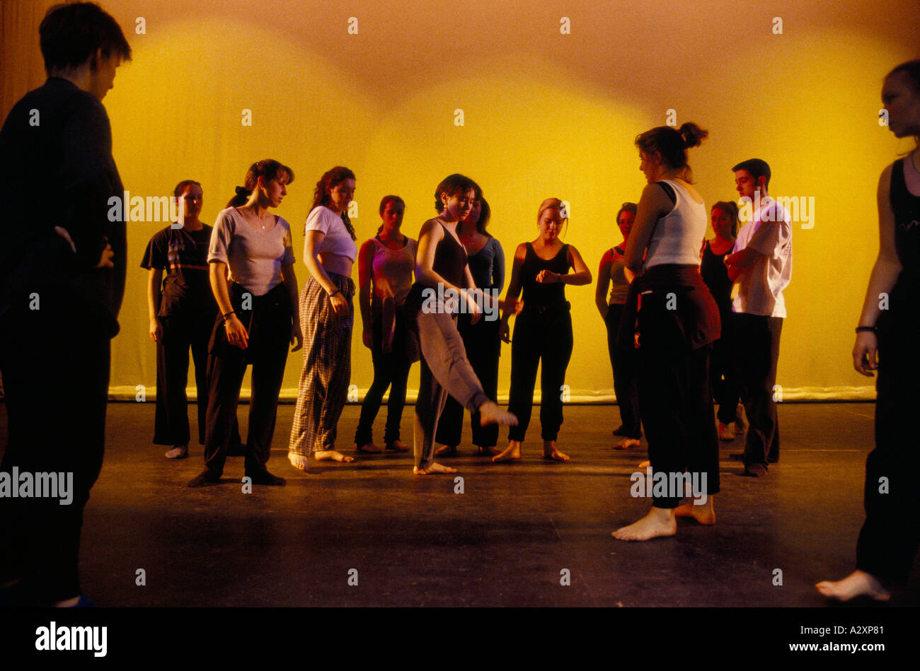 Dance students watch as one girl trys out a pointing leg movement during rehearsal at Liverpool Institute Of Performing Arts Stock Photo