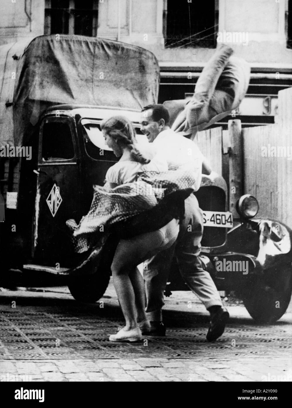 The photographer entitled this picture taken in 1956 An embarrassing moment in Madrid However the couple who are just walking arcoss the outlet to a subway ventilation shaft and have been surprised by the sudden rush of air produced by a passing train seem to be enjoying the episode Der Fotograf ueberschreibt dieses Bild 1956 mit Ein peinlicher Moment in Madrid Die Passanten hingegen die gerade einen der U Bahn Schaechte ueberqueren und im Luftzug des unterirdisch dahindonnernden Zuges stehen scheinen ihren Spass zu haben Curious Moments S 284 Stock Photo
