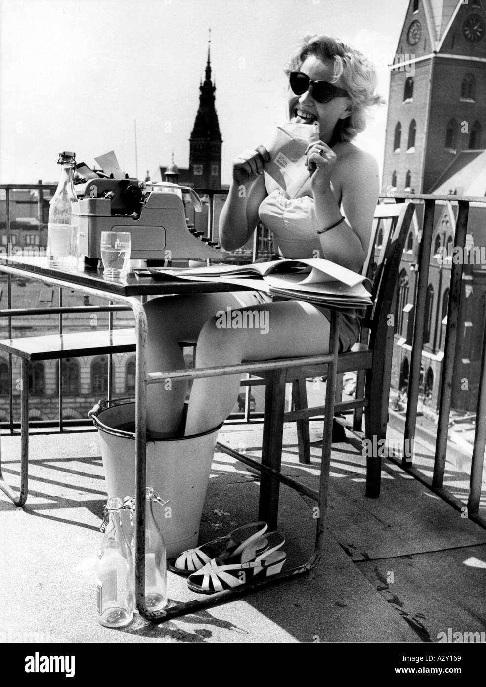 The unusually hot summer of 1955 led German workers to take no less unusual measures This Hamburg secretary has moved her workplace to the roof of the office building Die aussergewoehnlichen Temperaturen veranlassen im Sommer 1955 deutsche Arbeitnehmer zu besonderen Massnahmen Diese Hamburger Sekretaerin hat ihren Arbeitsplatz kurzerhand auf das Dach des Kontorhauses verlegt Curious Moments S 463 Stock Photo