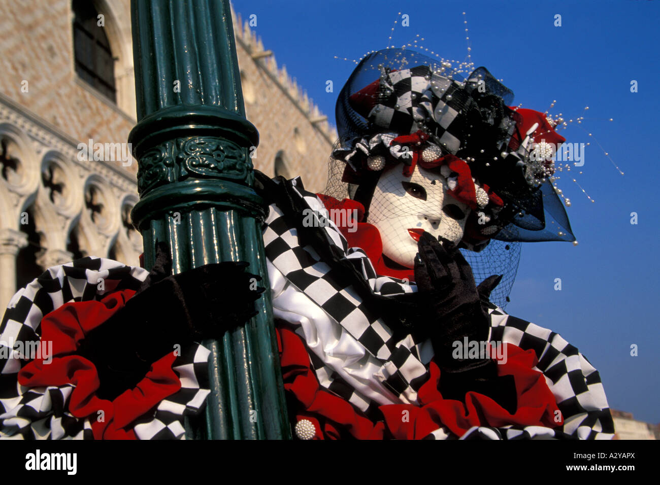 Black and White and Red Peirot Blowing Kisses from a Lamppost at Carnevale, Venice, Italy Stock Photo