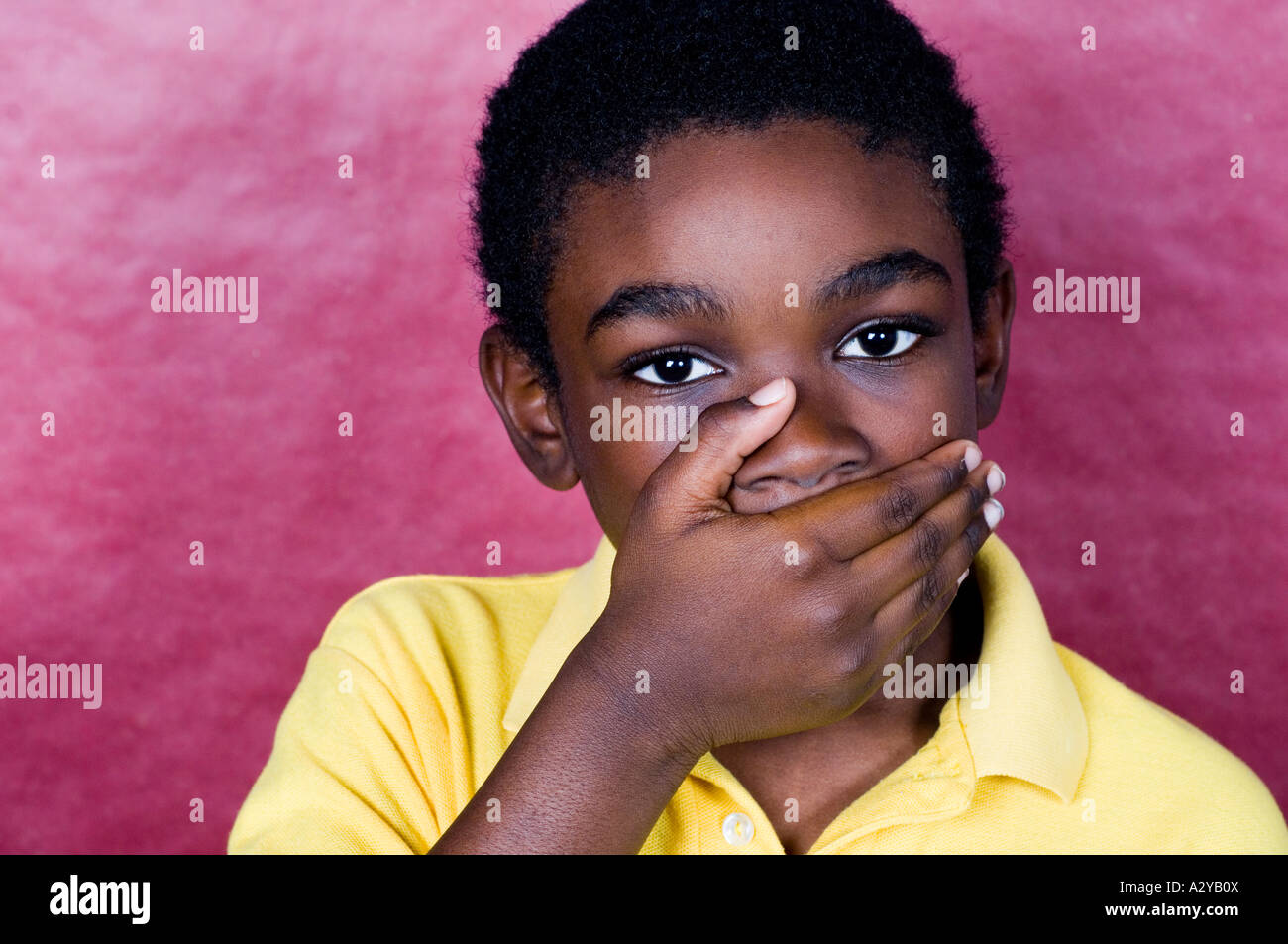 Young boy covering his mouth with his hand Stock Photo