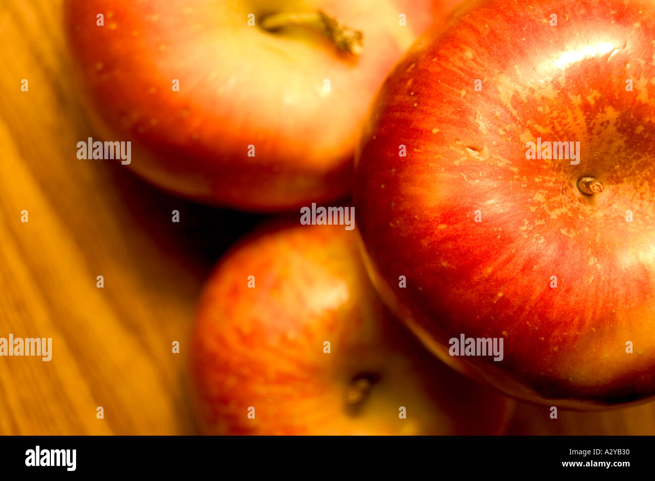 Three red apples stacked on a wood table top Stock Photo