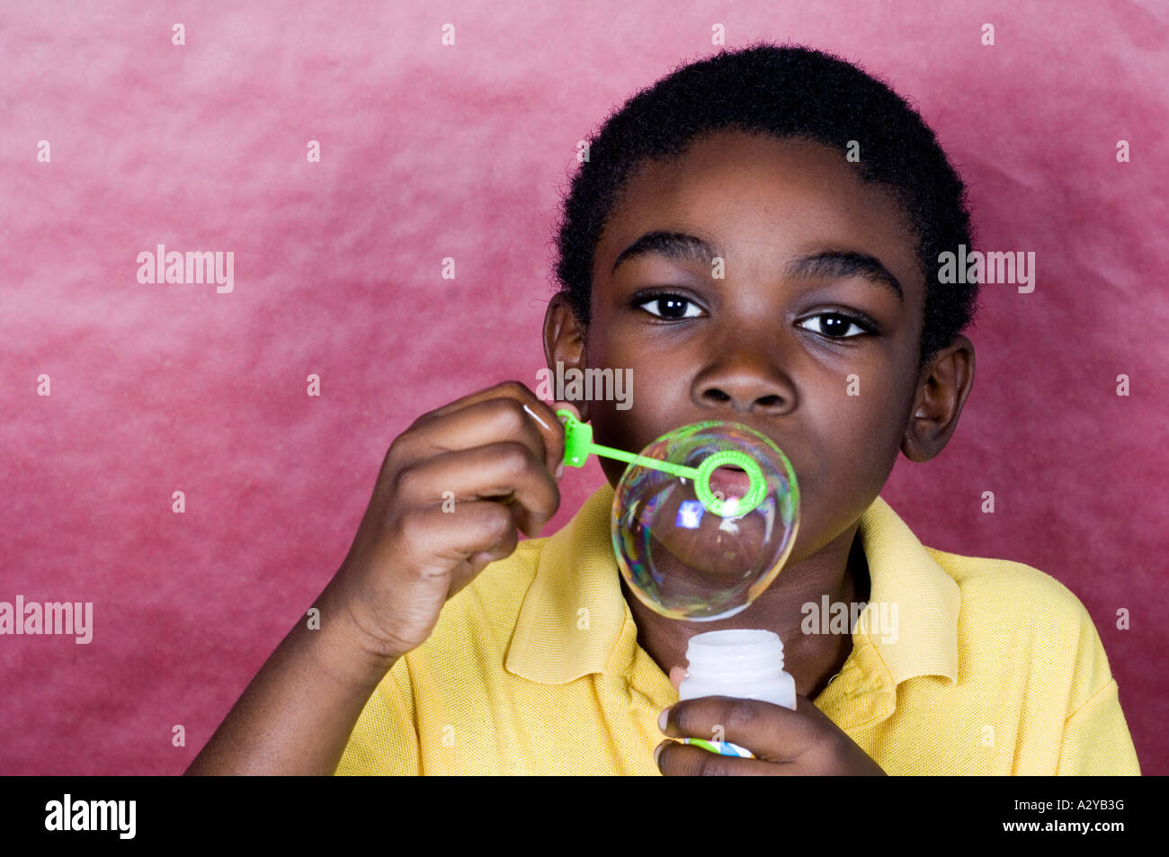 Boy looking at camera while blowing a bubble Stock Photo