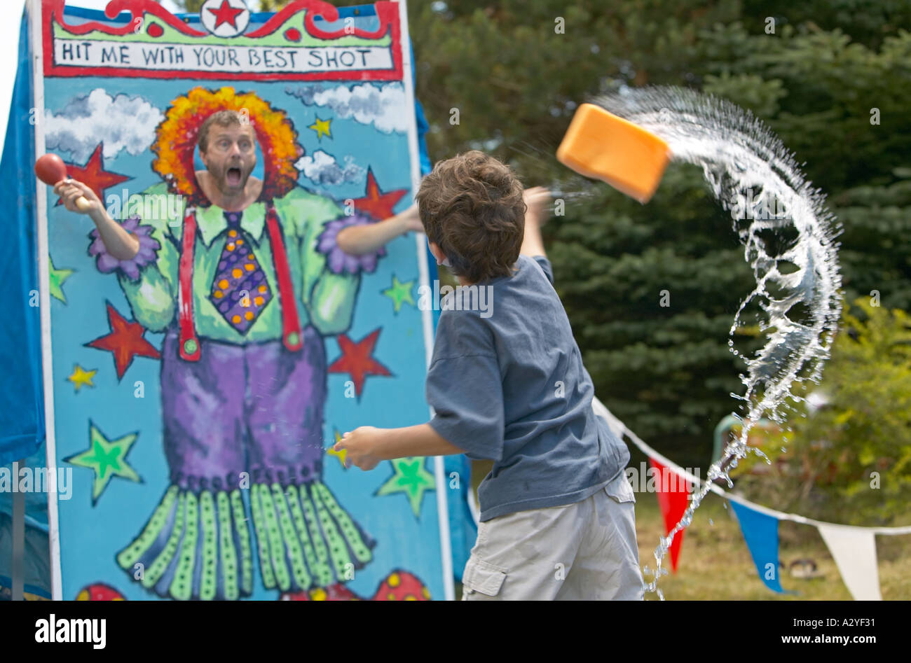 Caucasian 5 year old boy throws wet sponge at man at small town 4th of july festival Stock Photo