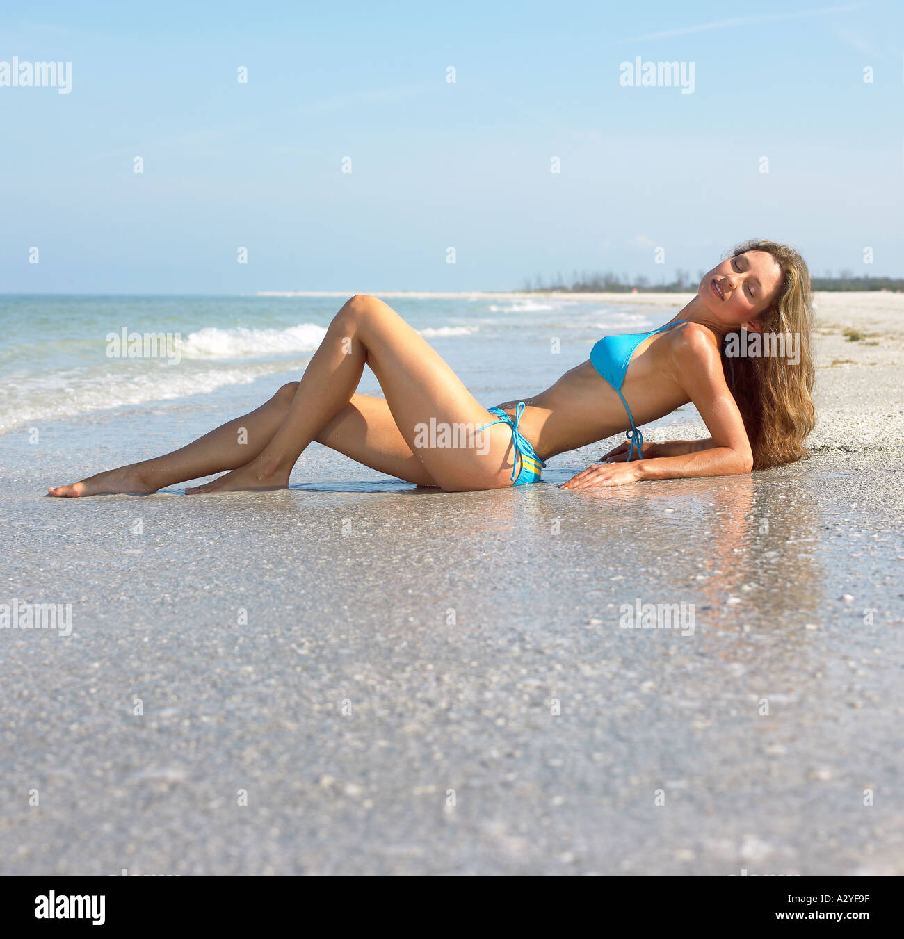 Caucasian female in blue bikini laying on beach Stock Photo
