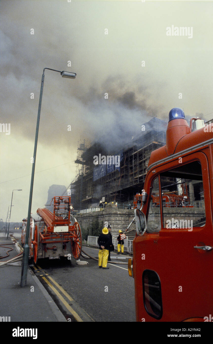 firemen attending fire with fire engines using ladders Stock Photo