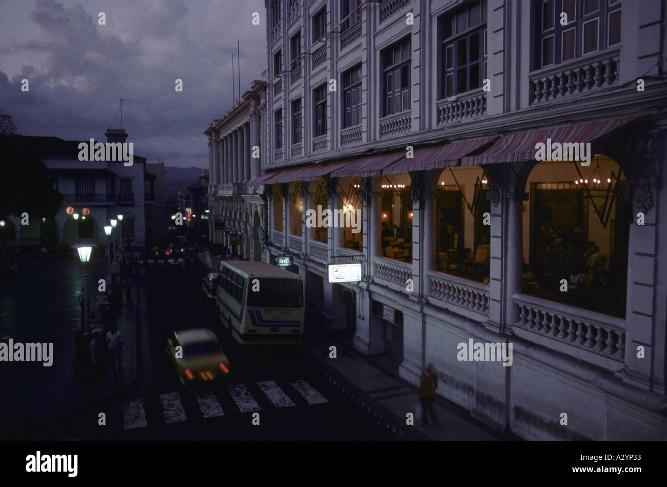 Old stone buildings, with a restaurant on a verandah, overlooking a street by night in the centre of Santiago, Cuba Stock Photo