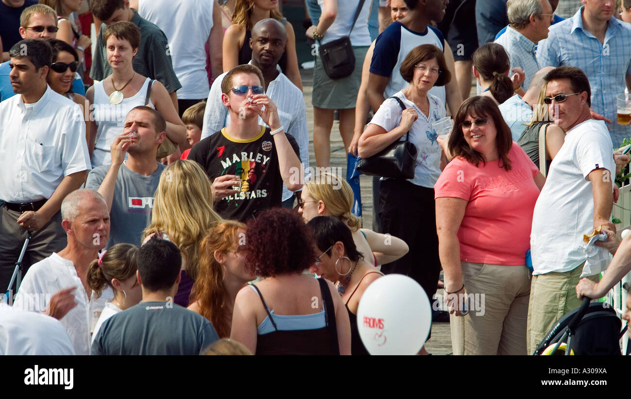 Crowd of people enjoying an outdoor event with two young men drinking