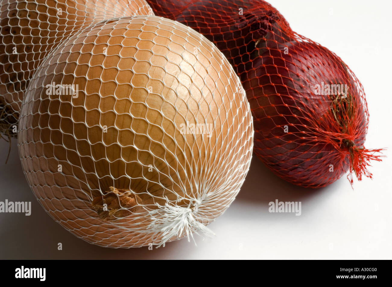 Spanish and Red Onions in mesh bags against white studio background Stock Photo