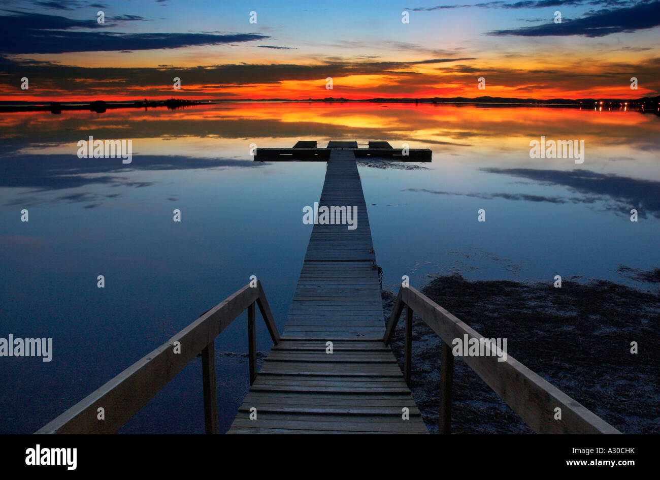 A red sunset reflected on a perfectly still lagoon with a jetty at Carleton Quebec Stock Photo