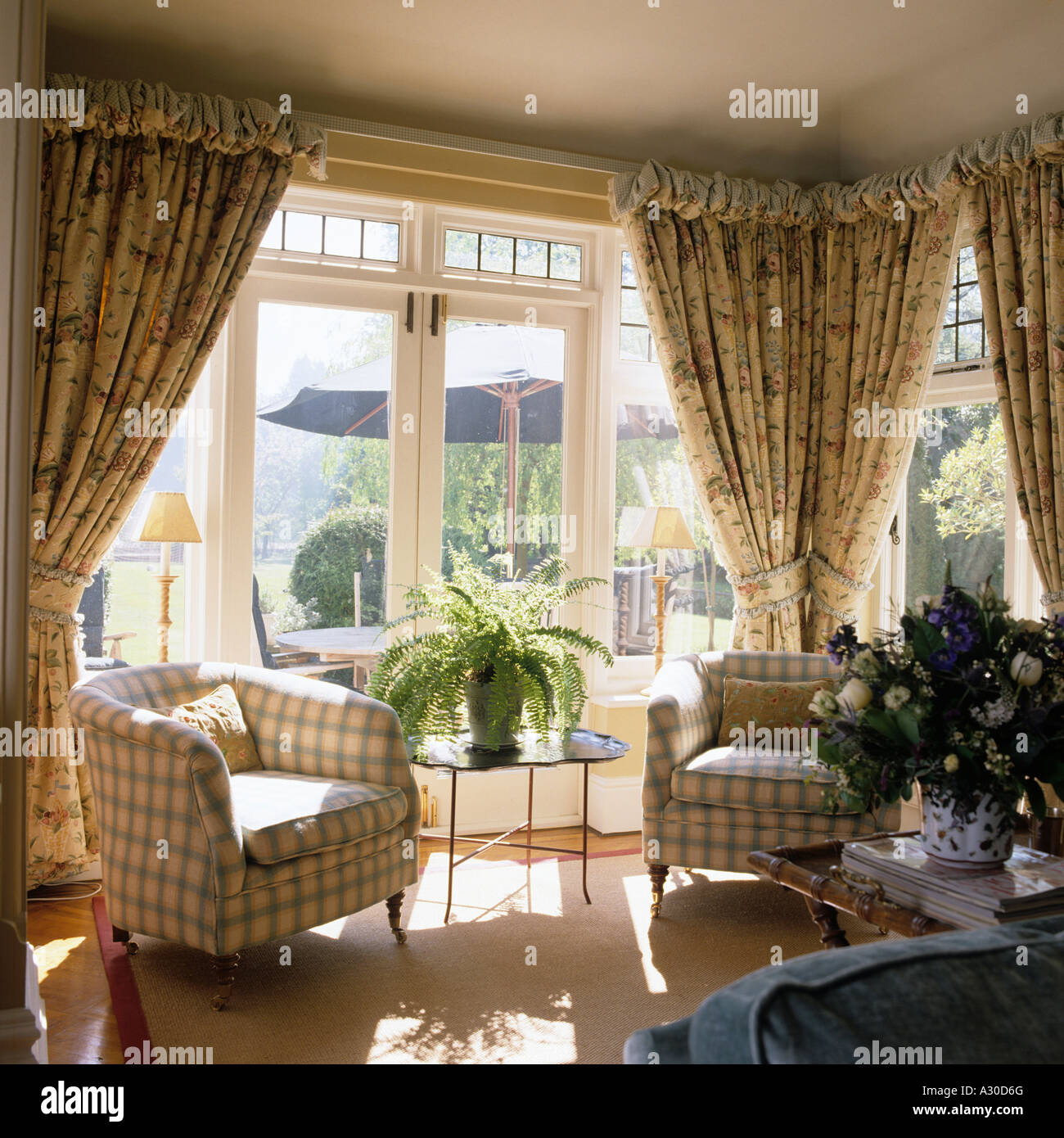 Matching armchairs in bay window with patterned curtains Stock Photo