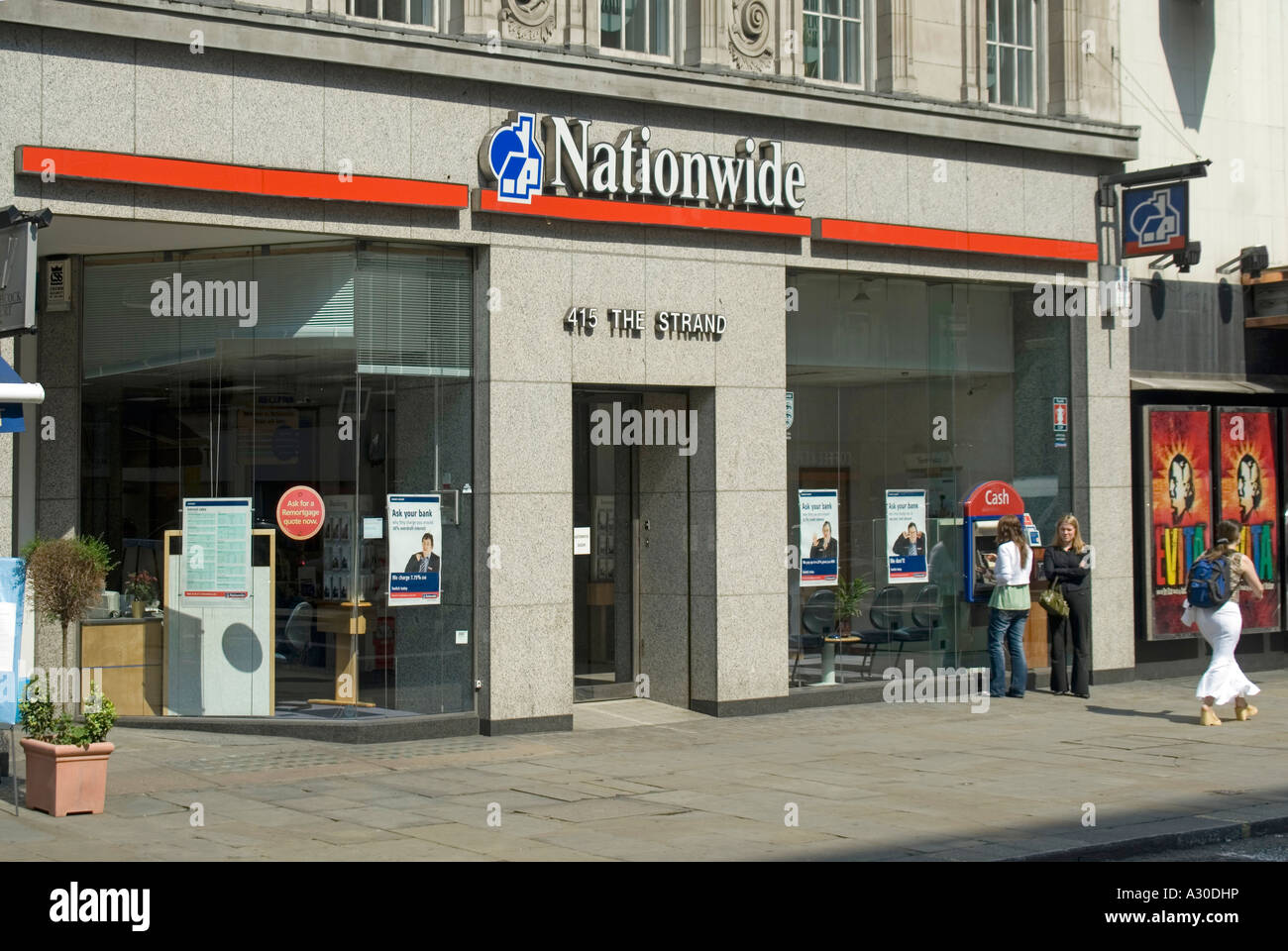 Front windows & entrance to branch premises of Nationwide Building Society people using hole in wall ATM cash machine The Strand London England UK Stock Photo