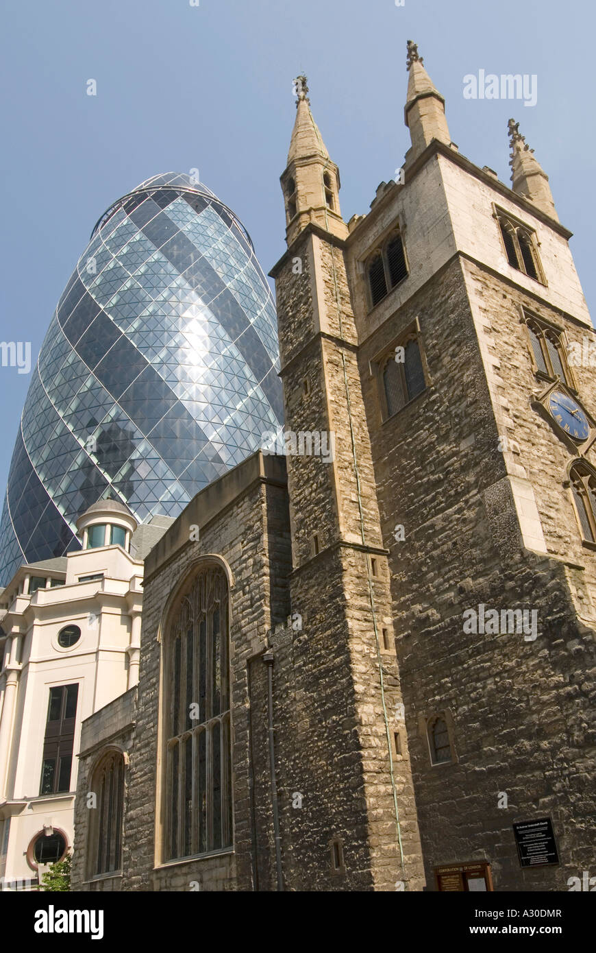 City of London ancient and modern view skywards of the tower of St Andrew Undershaft Church and the Gherkin office tower Stock Photo