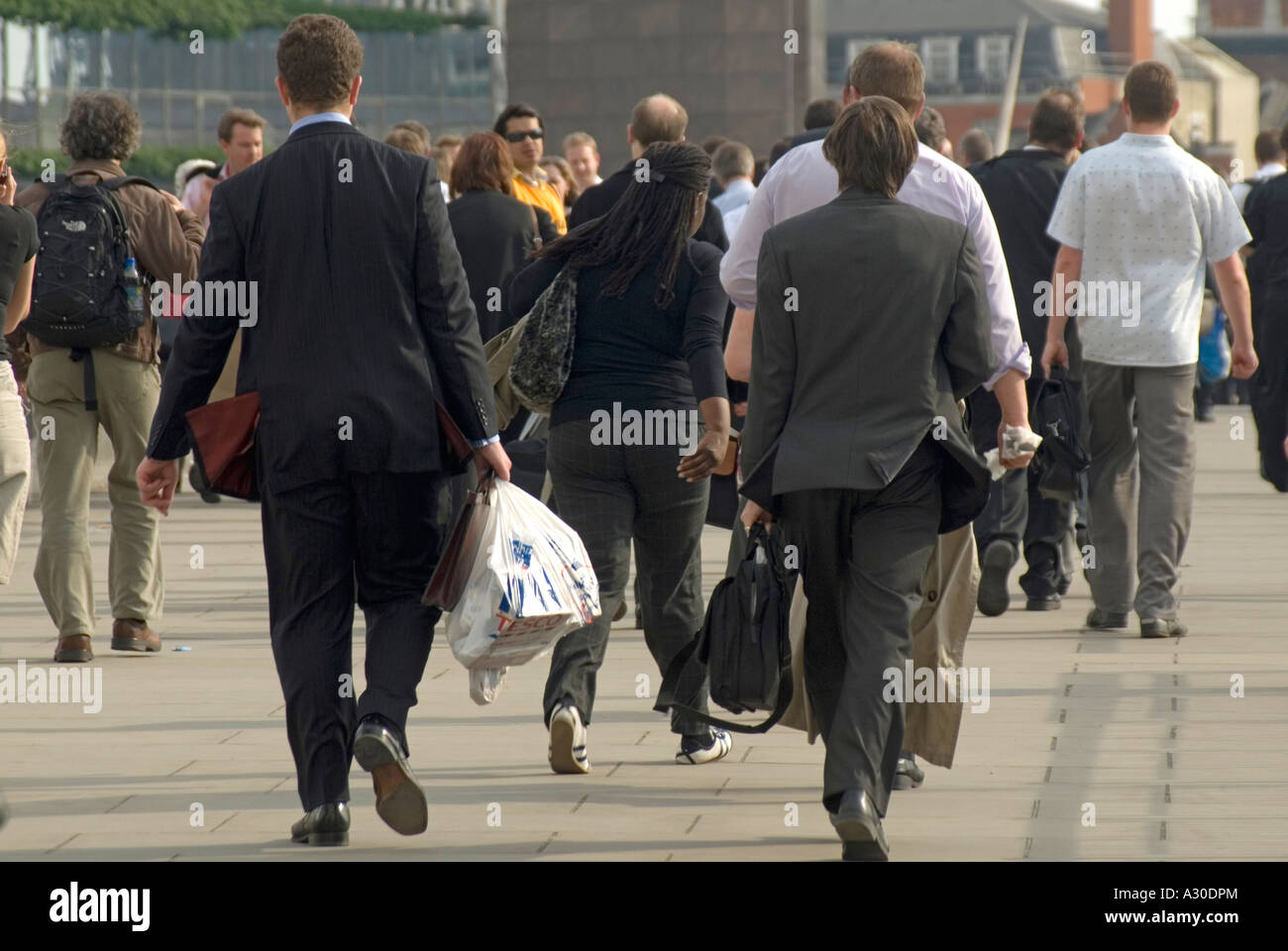 Evening rush hour group of office worker people on London Bridge walking from City of London to railway station for trains on south side England UK Stock Photo
