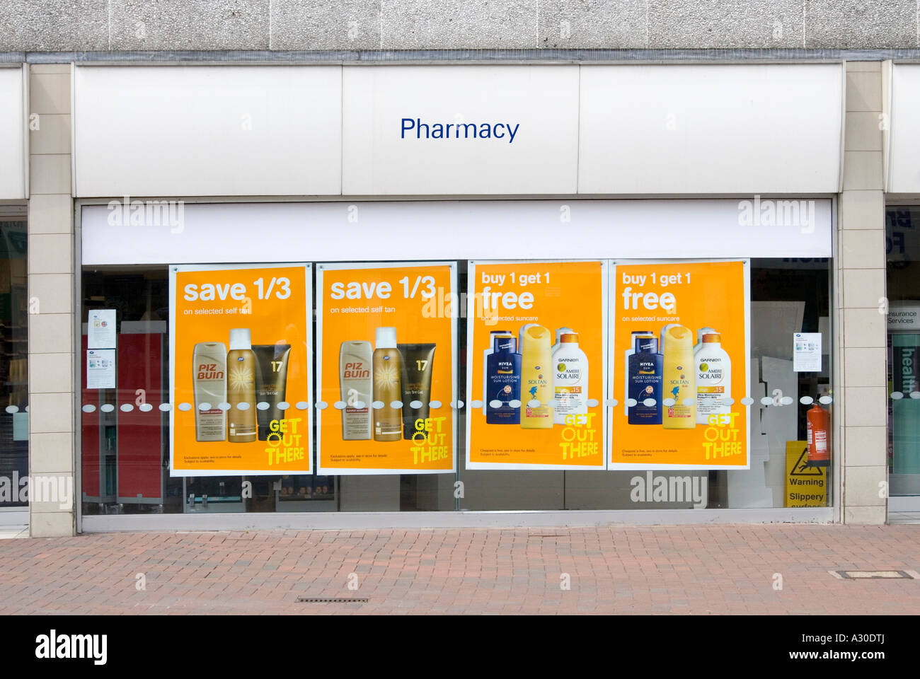 Window display of a typical high street Boots Pharmacy branch featuring posters promoting special offers on suntan products Stock Photo