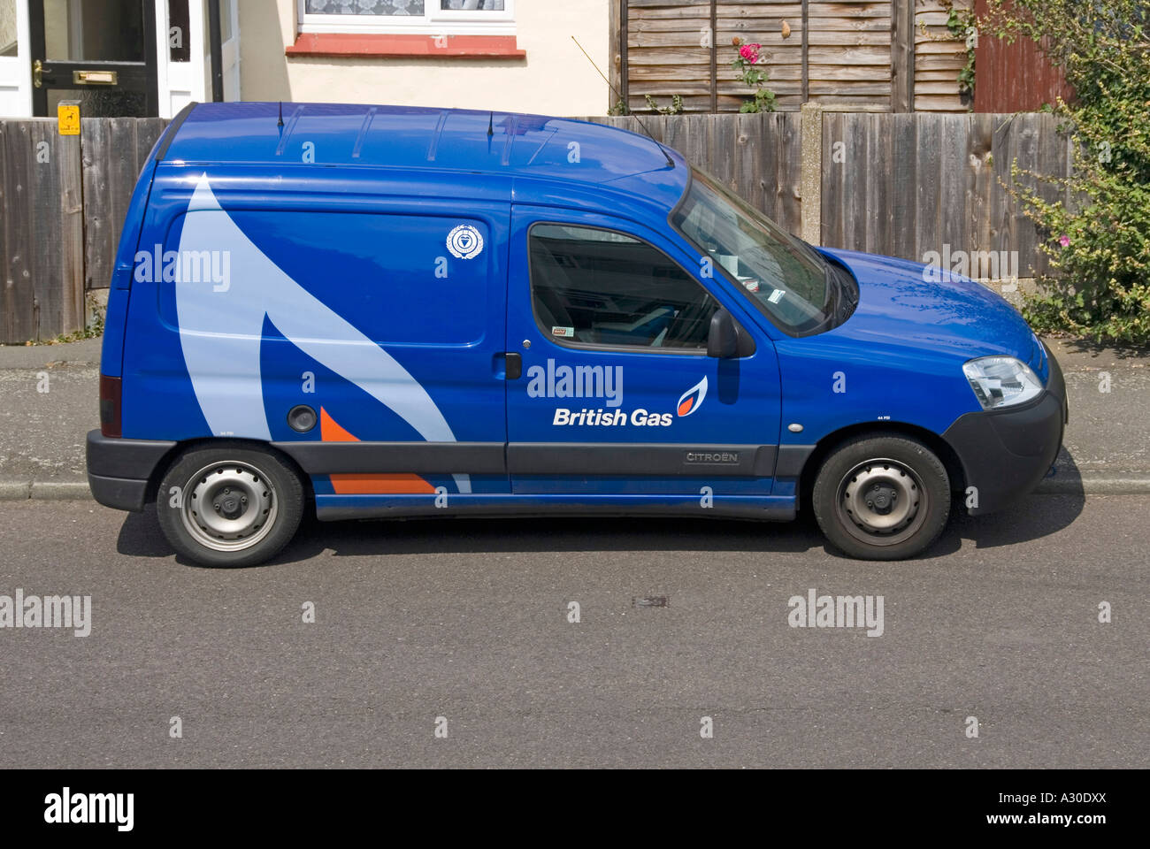 View from above looking down on blue British Gas service van parked outside house engineer indoors attending to gas central heating boiler England UK Stock Photo