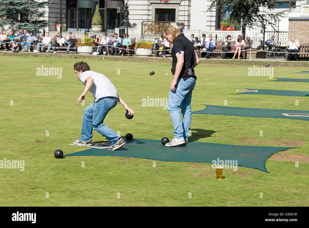 Lunchtime game of bowls on green at Finsbury Square watched by office workers on a hot summers day Stock Photo