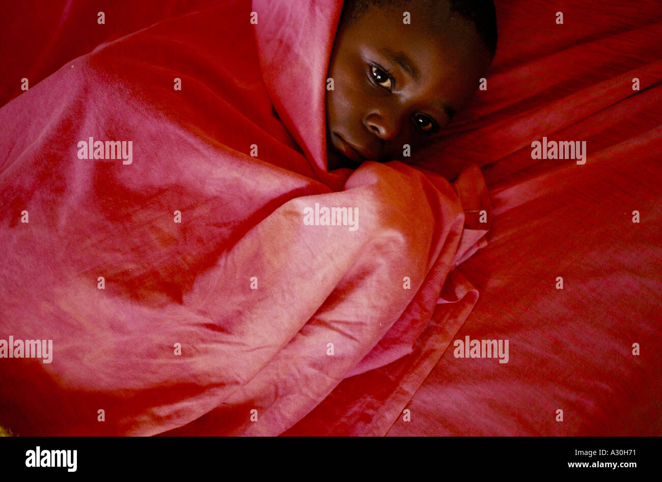A boy who has malaria shivers under a blanket at Shalom house Burundi Stock Photo Alamy