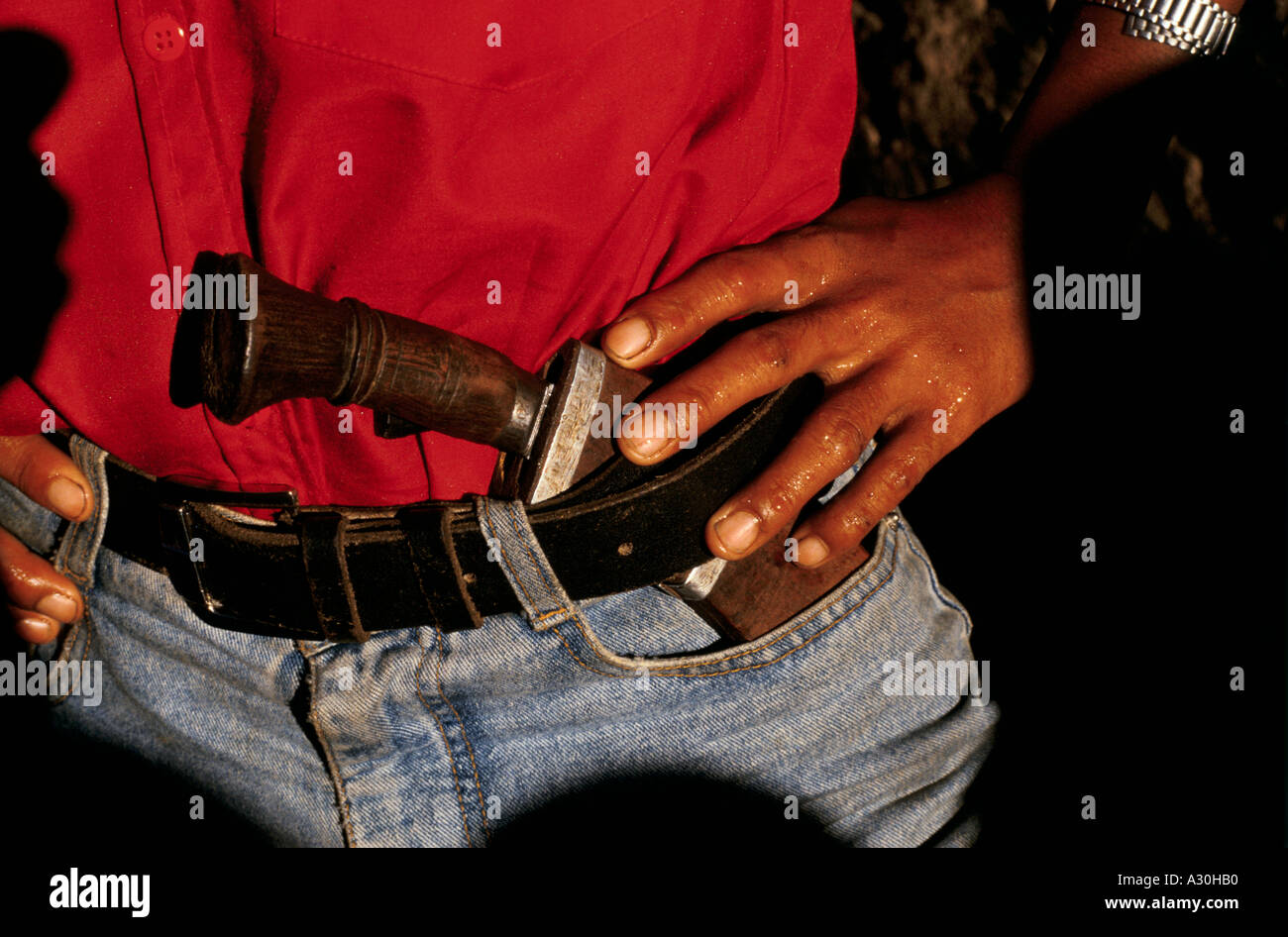 A Maoist rebel cadre in a red shirt with the traditional kukri knife native in the waistband of his jeans. Dolakha, Nepal Stock Photo