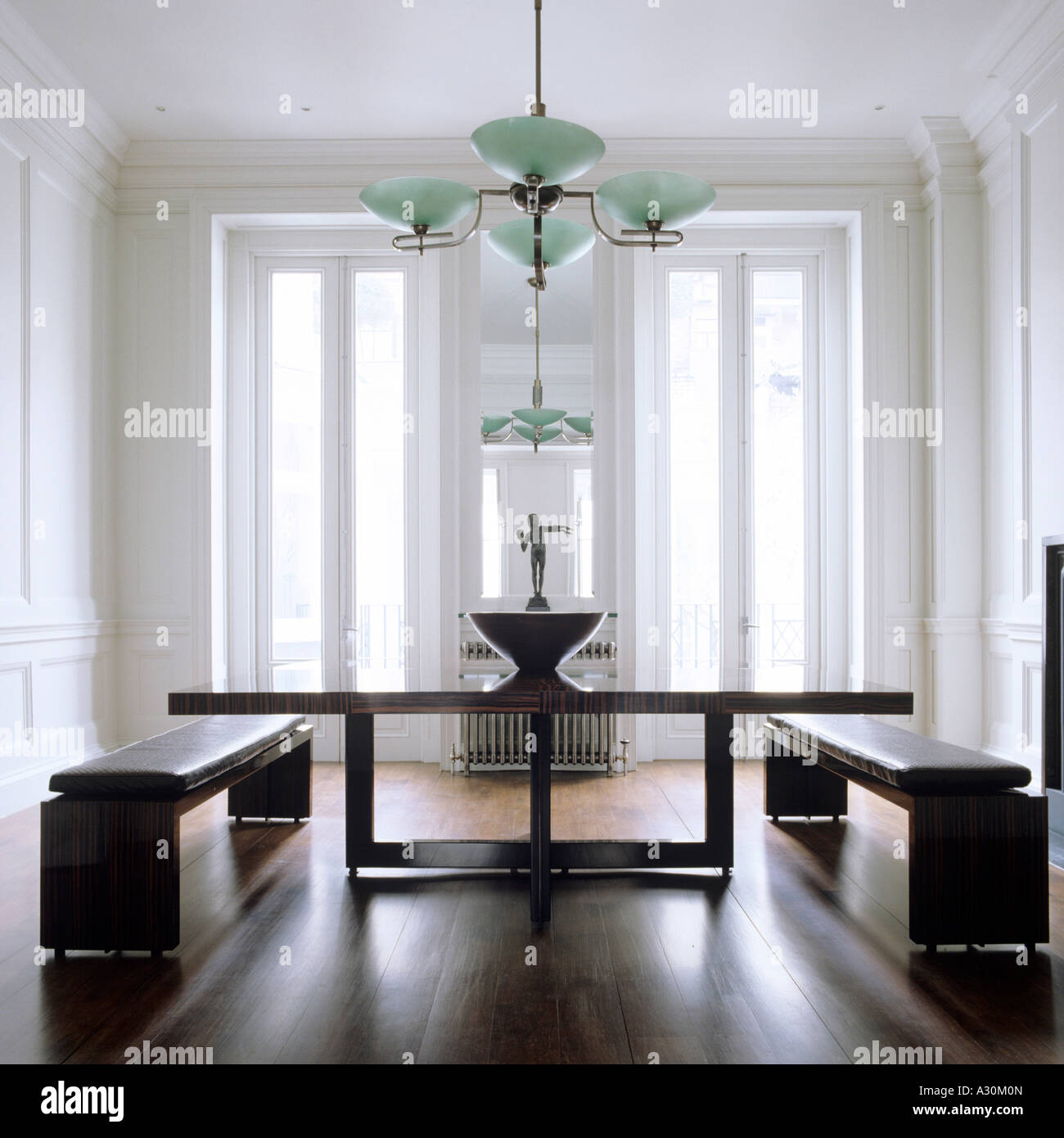 Green uplighter above polished wooden table with leather seat benches Stock Photo