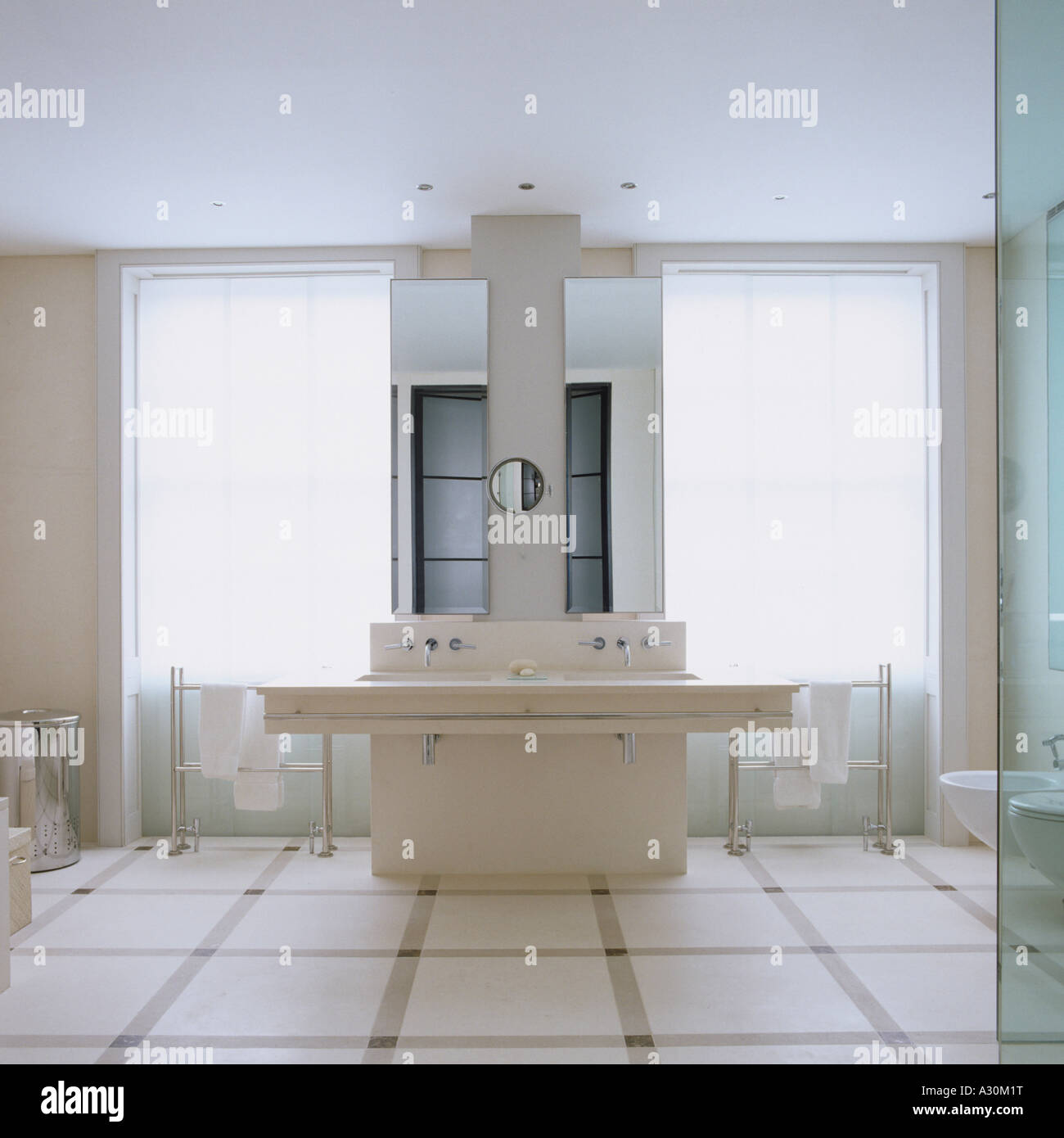Modern bathroom with double washbasins, windows and towel rails Stock Photo