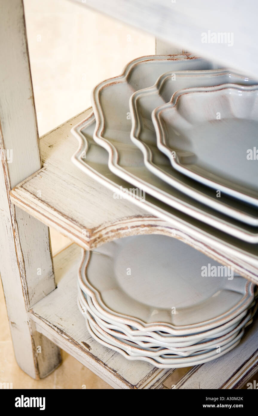 Stack of plates and serving bowls on worn painted shelving Stock Photo