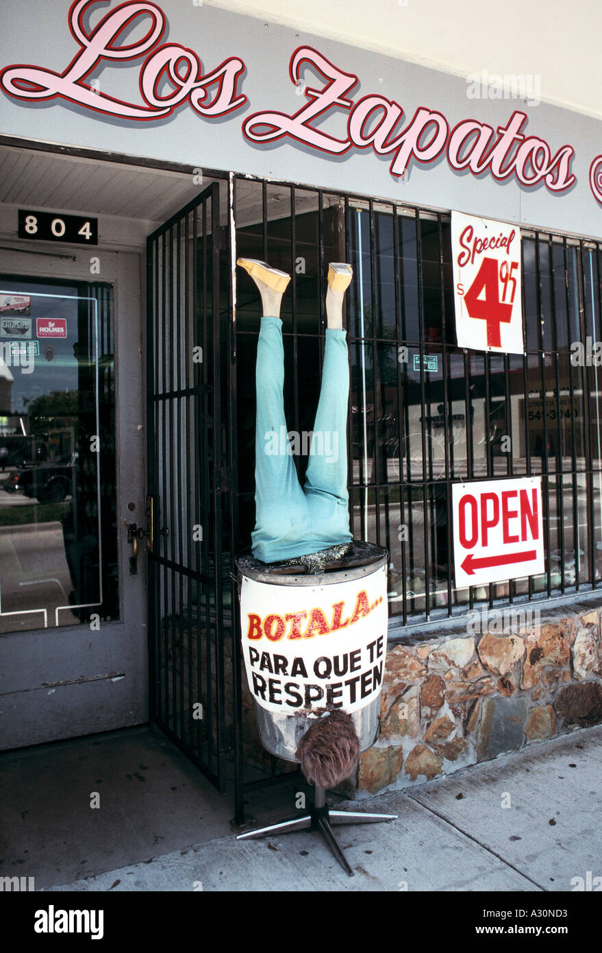 A pair of legs sticking out of a bin in front of a shoe shop in 'Little Havana', Miami, USA; a hispanic, mostly Cuban area. Stock Photo