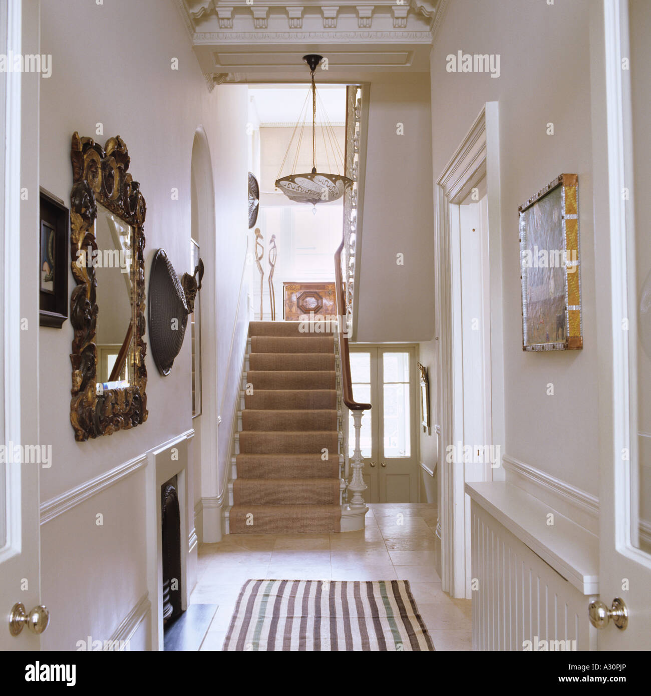 Artwork and staircase in hallway with striped rug Stock Photo