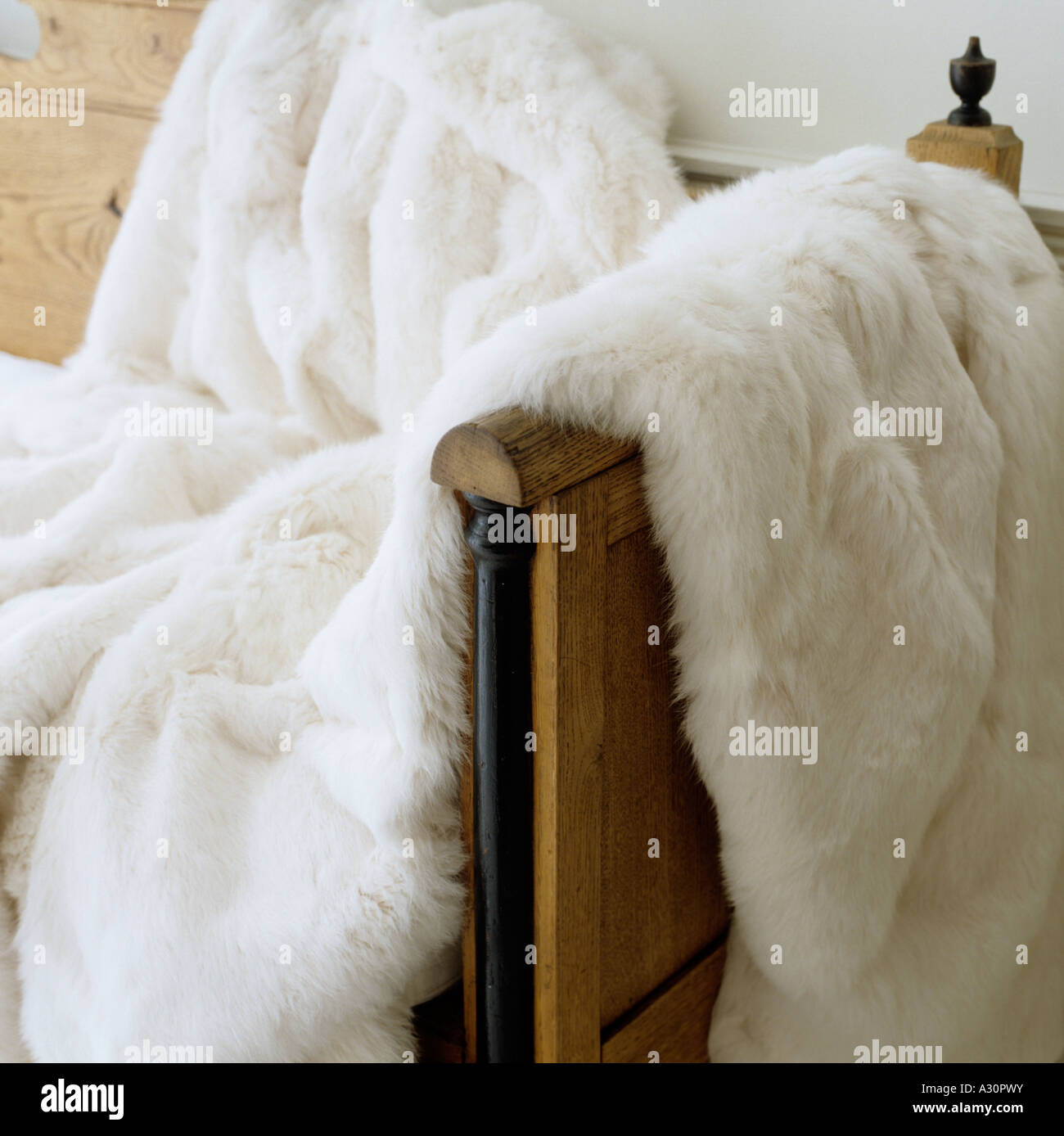 White fur throw draped over arm of wooden bench Stock Photo