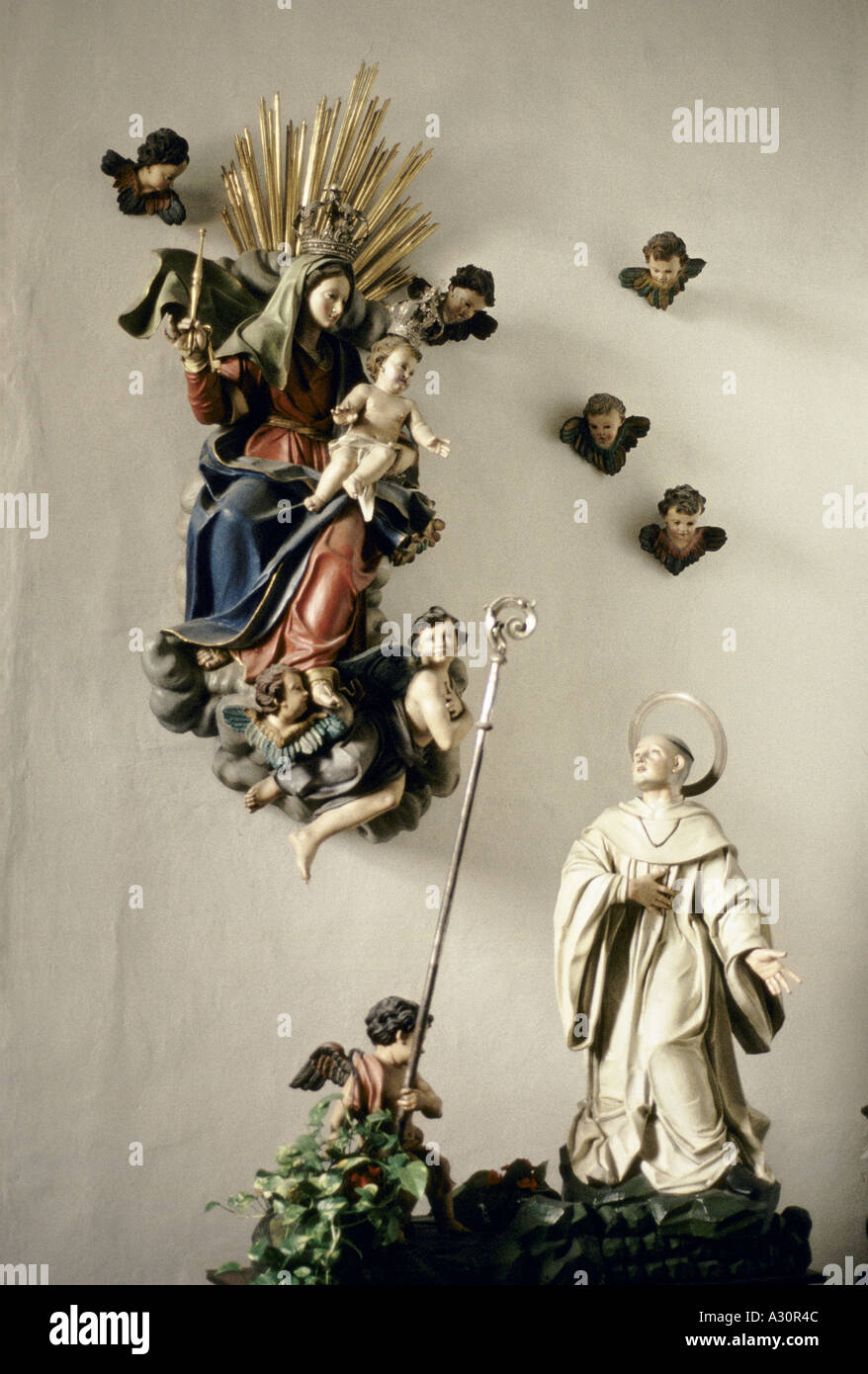 wall sculpture of the madonna holding baby jesus above standing male saint st benedict in benedictine church of st maria di castello italy 1992 1992 Stock Photo
