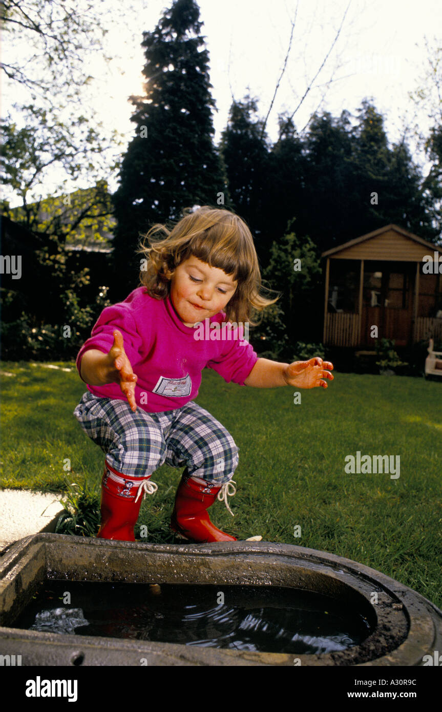 toddler playingh dipping her hands into water in stone trough in back