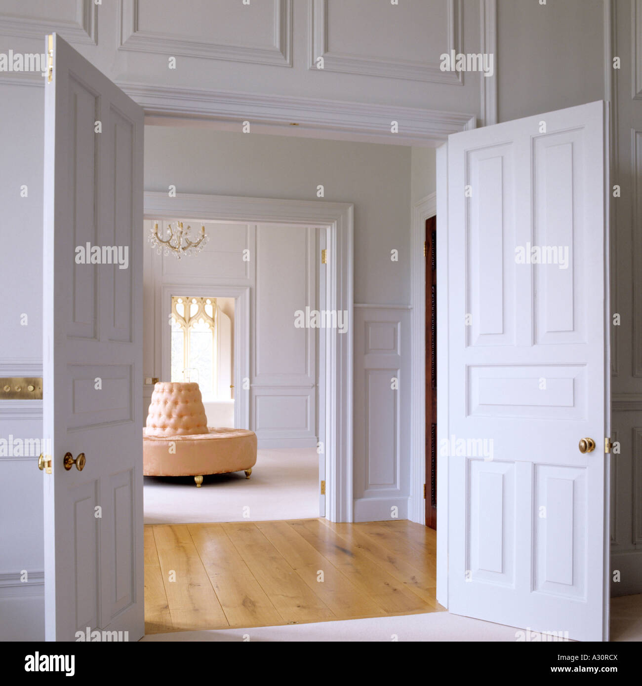 View through double doors across hallway to living room with  circular sofa Stock Photo