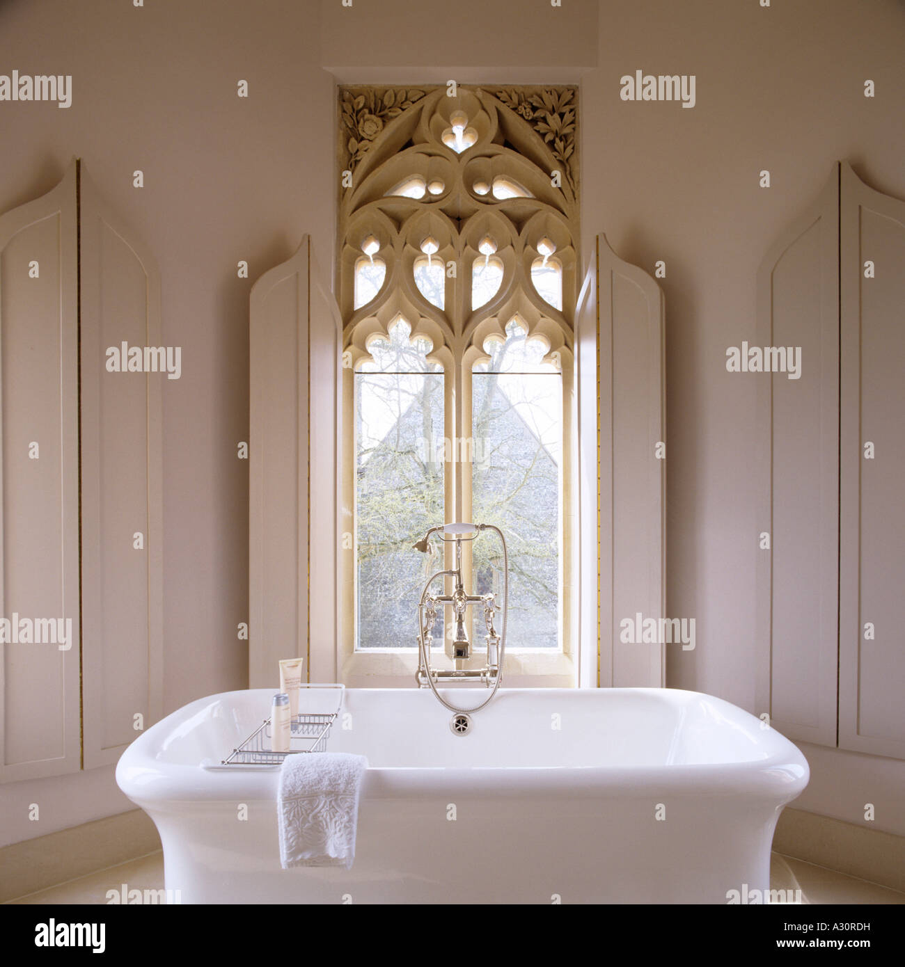 Freestanding bath in front of a large gothic window Stock Photo